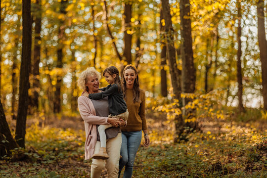 Mother, daughter and grandmother walking in the forest during autumn