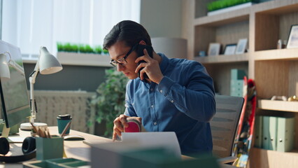 Creative businessman talking cellphone at cabinet. Man watching computer typing