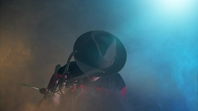 scary hand of  man is like a serial killer freddy with a glove sharp knives in the mist, background for Halloween