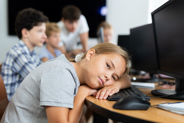 Girl student tired and lies down at computer desk during lesson