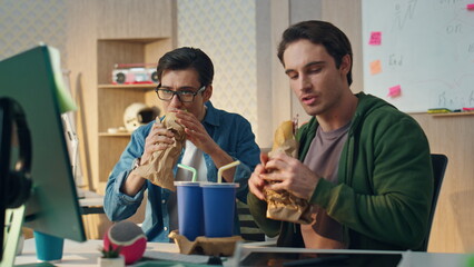 Gesturing colleagues having lunch looking monitor. Closeup coworkers pointing