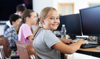 Portrait of female schoolgirl at computers in shool computer class