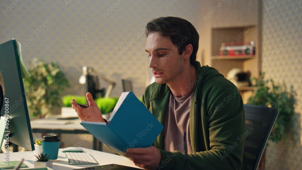Wall mural startup guy reading notebook having video call office closeup. man making notes