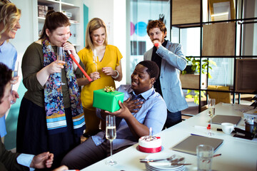 Young and diverse group of business people having a birthday party in the modern office