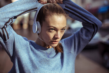 Young fit woman tying her hair before going on a jog in the city streets