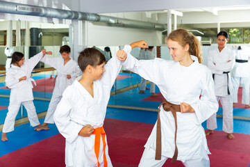 Young children sparring in pairs to practice new moves in karate class