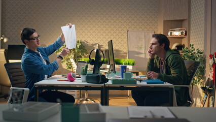 Business coworkers discussing project together at office. Man crumpling paper