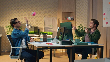 Positive guys playing ball communicating sunny office. Freelancers giving five