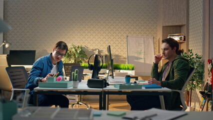Two people communicating workplace interior. Positive man drinking tea at office