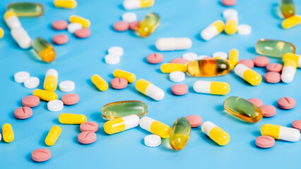 Many colorful pills on blue background. Medical treatment with medicine, omega 3 vitamins and...