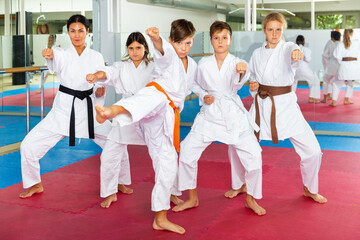 Female trainer is training young teenagers in karate class