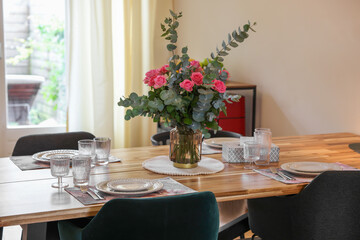 Beautiful table setting with bouquet indoors. Roses and eucalyptus branches in vase