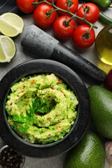 Delicious guacamole and ingredients on grey table, flat lay