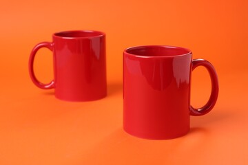 Two red ceramic mugs on orange background