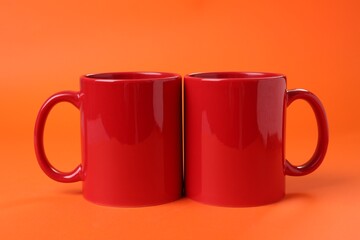Two red ceramic mugs on orange background