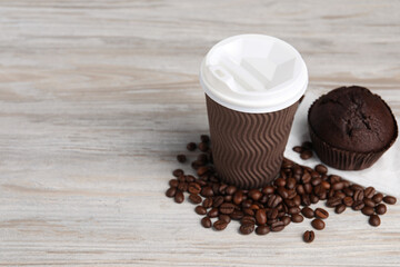 Paper cup, coffee beans and muffin on wooden table, space for text. Coffee to go