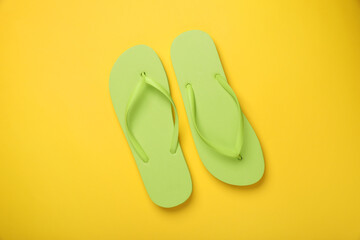 Stylish light green flip flops on yellow background, top view