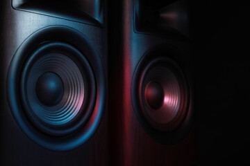 Modern sound speakers in neon light on black background, closeup
