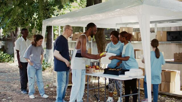 Voluntary individuals assist the less fortunate at a food bank. Meal donations are distributed by volunteers in a friendly manner, exemplifying the spirit of community and charitable work.