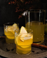 Autumn ice cider cocktail with apple and pear on the gray table. Glass of sangria or punch