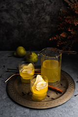 Autumn ice cider cocktail with apple and pear on the gray table. Glass of sangria or punch