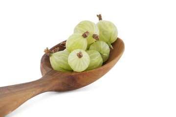 Gooseberries in a wooden spoon over white background