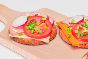 Crispy Cracker Sandwiches with Tomato, Sausage, Cheese, Green Onions and Radish on Cutting Board. Easy Breakfast. Quick and Healthy Sandwiches. Crispbread with Tasty Filling. Healthy Dietary Snack