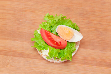 Rice Cake Sandwich with Tomato, Lettuce and Egg on Bamboo Cutting Board. Easy Breakfast. Diet Food....