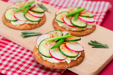 Light Breakfast or Diet Eating - Crispy Cracker Sandwich with Cream Cheese, Fresh Cucumber, Green Onions and Radish on Wooden Cooking Board on Magenta Background