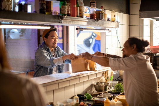 Young Asian delivery man picking up a sushi order from a sushi restaurant or bar