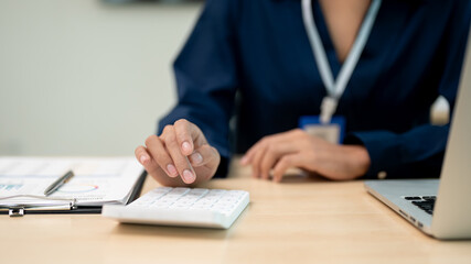 Close up view of businesswoman working with calculator at her office desk.