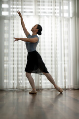 Beautiful woman performing a ballet dance, practicing her dance move at home.