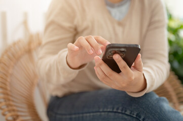 A woman using her smartphone to chat with her friends while relaxing in a minimalist cafe.