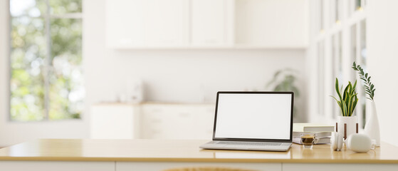 A white-screen laptop mockup on a wooden desk in a modern, minimalist white kitchen. - obrazy, fototapety, plakaty