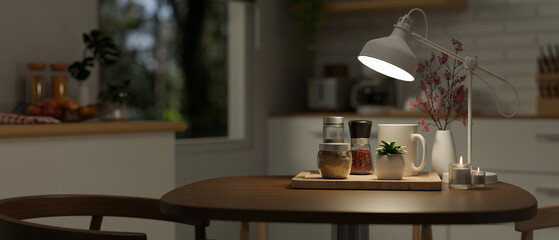 A hardwood dining table with seasoning bottles and a table lamp in a modern kitchen at night.