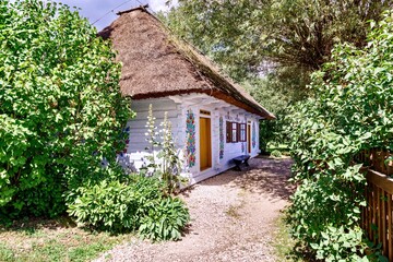 A fragment of a traditional Polish house with a thatched roof and a wooden door painted in the national style.