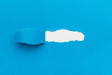A torn blue paper from under which a white one peeks out.