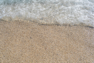 A soft wave runs on a sandy shore on a summer day. Empty space can be used as background for display or montage your top view products.