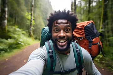 Schilderijen op glas Happy traveller black man with backpack taking selfie picture in forest - Travel blogger taking self portrait with smart mobile phone device outside - Life style and technology concept © sam