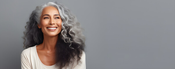 Black middle age woman portrait with healthy face skin. Open smiling beautiful aging mature woman with long hair. Beauty and cosmetics skincare advertising concept - obrazy, fototapety, plakaty