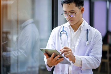 Asian male doctor in white coat with stethoscope, having tablet Medical students in the hospital