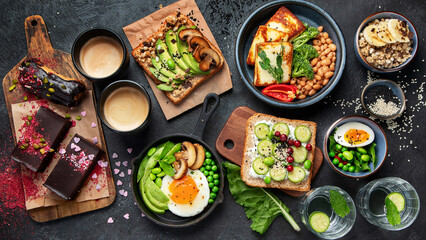 Tasty food with avocado toast, vegetables, eggs on dark background. Helthy breakfast concept