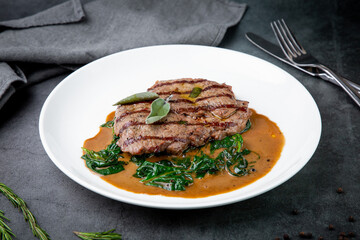 steak in gravy with herbs on it on a white plate