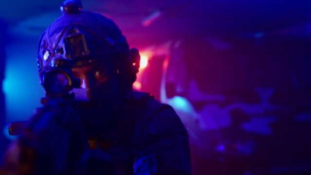 A close-up portrait of a Special forces soldier. A special forces soldier with an automatic weapon aims at the target and looks around. During a military operation.