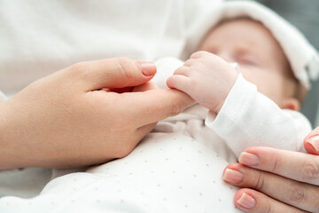 Newborn finds solace holding mother's finger during illness. Concept of maternal comfort in distressing times