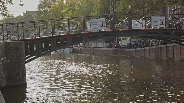 Panning past bridge over canal with warning signs in the Amsterdam Red Light District