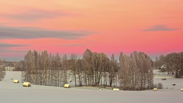 Pink Timelapse Skies Over Winter Landscape with Wooden Huts in Latvia