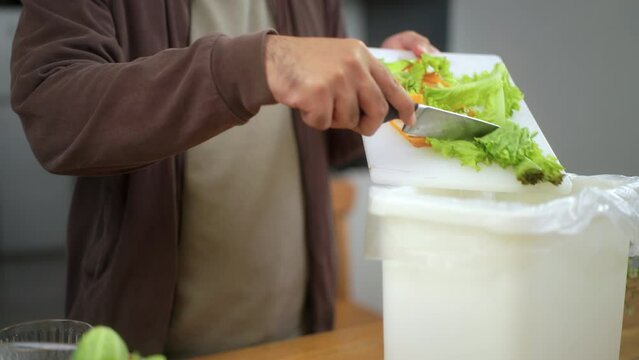 Ecology compost supply kitchen waste sorting waste vegetable peels from cutting board to recycle composter environmentally friendly. Man throws leftover fruit peel and vegetables reduce zero waste.