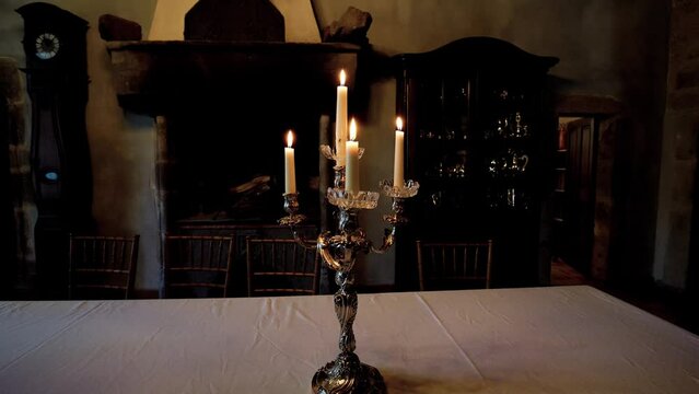 Captivating close-up arc shot of vintage antique candle holder with candles burning placed on table at night