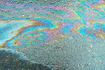 Obraz premium Leakage of oil or gasoline from under the car on the asphalt in the parking lot